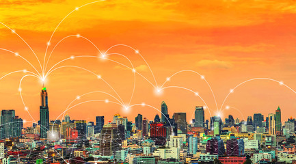 Wireless network connection technology icons over city at sunset.