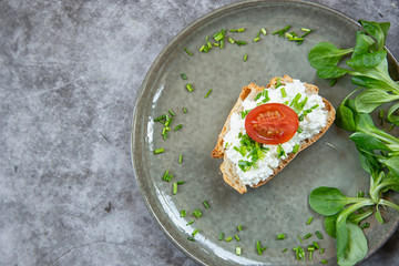 Breakfast. A piece of bread smeared with cottage cheese with green onions and tomato