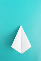 Flat lay of white paper plane on pastel blue color background