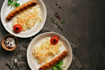 Fried sausages with sauerkraut on a dark rustic background. Flat lay, copy space.