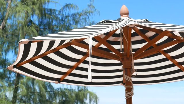 Detail of a pool umbrella with black and white striped texture during a sunny day. 4K Resolution