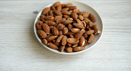 Healthy food  for background image close up almond nuts. Texture on white grey table top view. Nut on the cup plate