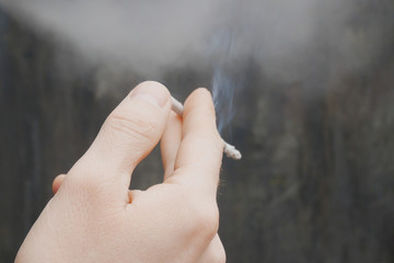 man smokes, hand with a cigarette and smoke closeup, bad habits concept
