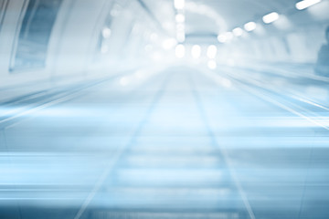 blurred background metro escalator / light blue background movement city infrastructure subway