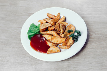 Plate with baked potato wedges and sauce