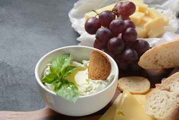 Cheese platter with assorted cheese, grapes, snacks on dark background. Italian, French cheese starter