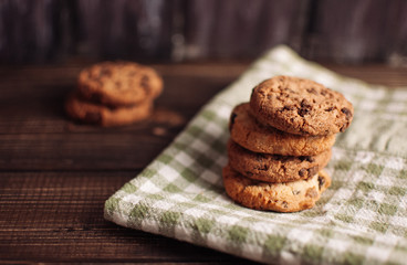 Chocolate chip cookies with green napkin on a wooden table.