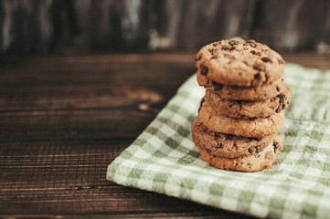 Chocolate chip cookies with green napkin on a wooden table.