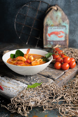 Tom Yam soup with shrimp, squid and hot pepper on textured wooden board.The concept of national cuisine