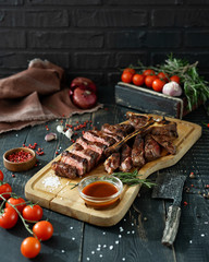Roasted meat on a bone and fresh vegetables on a wooden cutting Board in rustic style