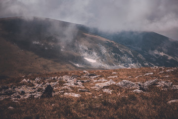 A landscape with a lake and beautiful clouds and rocks.
