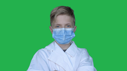 In slow motion on the background of a chromakey a young guy (boy) in a doctor's uniform in a mask. Concept of: Green background, Chromekey, Young doctor, Fashionable, Blond, Doctor.