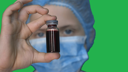 In slow motion on the background of a chromakey a young guy (boy) in a doctor's uniform in a mask. Concept of: Green background, Chromekey, Young doctor, Fashionable, Blond, Doctor.