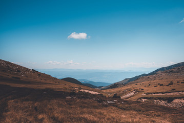 A landscape with a lake and beautiful clouds and rocks.
