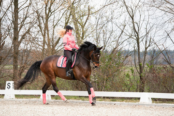 Reiterin galoppiert mit ihrem Pferd im Winter auf einem Reitplatz