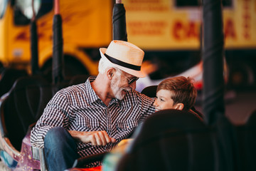 Grandfather and grandson having fun and spending good quality time together in amusement park. They...