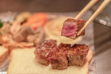 Barbecue rib eye steak, Selected focus on a dry aged Wagyu entrecote steak on chopsticks.