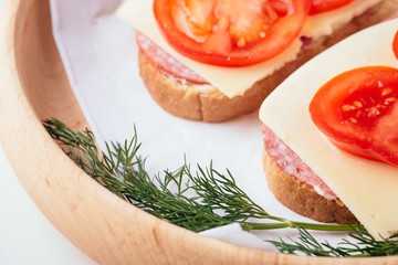 Quick cooking sandwiches with ham meat cheese tomato dill on wooden plate