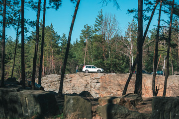 man opening suv car trunk at cliff in forest