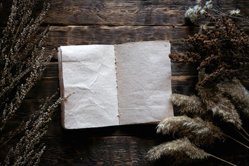 Dried herbs and a blank page open book mock up on a wooden table background with copy space. Druid book.