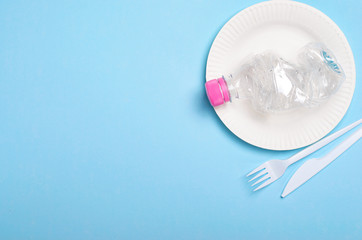 Plastic Bottle, Cutlery and Plate over Light Blue Background