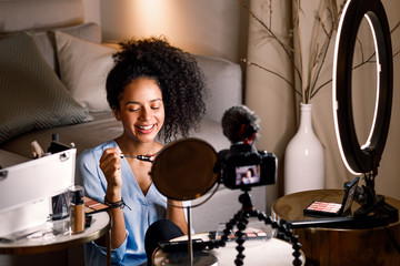 Smiling beauty vlogger holding a mascara. Woman recording video content.