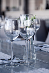 Modern restaurant setting, glass vase with bouquet flowers on table in restaurant. Wine and water glasses stand on wooden table. Concept banquet, birthday, conference, wedding