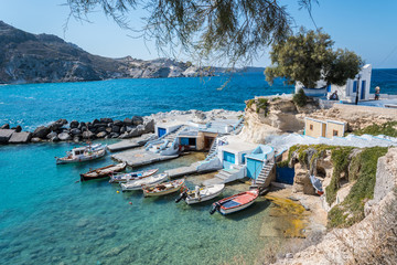A small harbor with colorful fishing boats and crystal clear turquoise waters in Mandrakia village in Milos island, greece