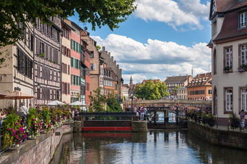 People walking on a streets of the "Petite France" district in Strasbourg. "Petite France" is a historic area in the center of Strasbourg where are many historic half-timbered houses.