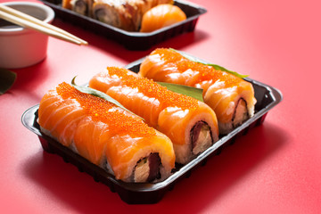 Philadelphia roll sushi with salmon, avocado, cream cheese on red background.