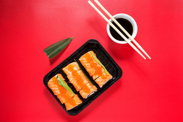 Philadelphia roll sushi with salmon, avocado, cream cheese on red background. Japanese food.