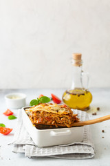 Traditional italian lasagna with vegetables, basil, minced beef meat, tomato and cheese on concrete background.