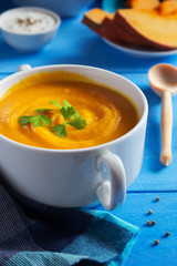 Pumpkin cream soup with parsley on blue table