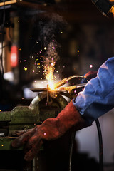Welder is welding in the garage,industrial Worker labourer at the factory welding steel structure