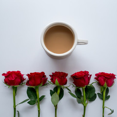 Cup of tea and two slices of sponge cake in a plate on a white table with a white and red tea towel. Top view. Square format.