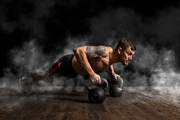 Muscular man doing pushups on kettle ball