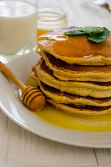 Pancake with milk on a white plate and wooden table.