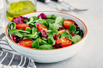 Fresh green salad bowl with radicchio, tomatoes and pumpkin seeds.