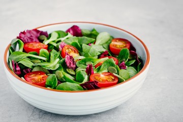 Fresh green salad bowl with radicchio, tomatoes and pumpkin seeds.