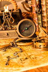 Fototapeta na wymiar Antique compass on the background of a treasure chest with gold and books. Vintage style. 1565 old map of the year.