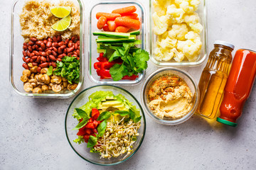 Healthy vegan food in glass containers, top view. Rice, beans, vegetables, hummus and juice.