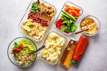 Healthy vegan food in glass containers, top view. Rice, beans, vegetables, hummus and juice.