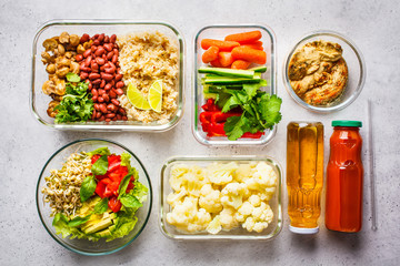 Healthy vegan food in glass containers, top view. Rice, beans, vegetables, hummus and juice.