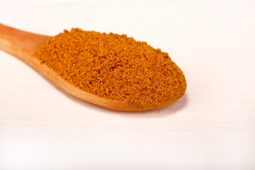Wooden serving spoon full of curry spice powder isolated over the white background