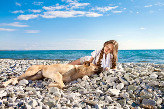 A brown dog and a girl are resting on the beach. Girl and dog