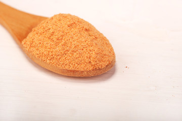 Wooden serving spoon full of turmeric spice powder isolated over the white background