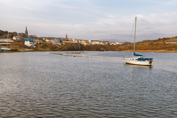 Fototapeta na wymiar Boat in Clifden bay with village in background