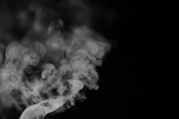 White smoke on a black background. Texture of smoke. Clubs of white smoke on a dark background for an overlay