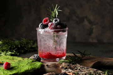 Refreshing summer drink with syrup, raspberry, blackberry and ice on dark background, Glass with cold and healthy beverage