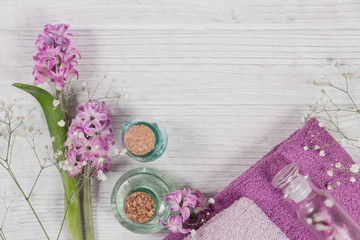 Abstract composition of pink hyacinths flowers, towels and bottles of organic cosmetic with essential oil